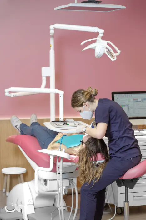 Praticienne soignant une patiente sur un fauteuil rose en salle d'orthodontie — Cabinet 21 Libération